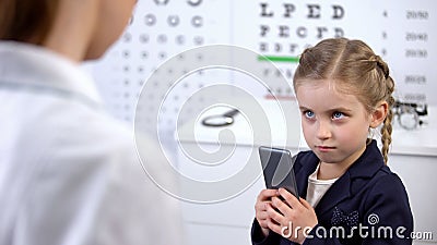 Optician trying to take cellphone from naughty child, video games damage sight Stock Photo