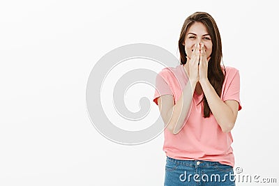 Optimistic carefree attractive woman with long brown hair, chuckling and covering mouth with palms, trying not to laugh Stock Photo