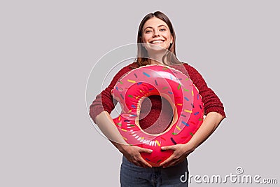 Optimistic cheerful girl holding rubber ring pink donut and looking at camera with toothy smile, enjoying summer Stock Photo