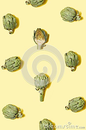 Optimistic pattern made of superfood tasty artichokes. Pastel yellow background. Flat lay vertical composition Stock Photo