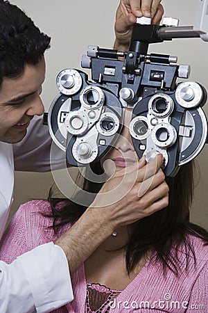 An Optometrist Adjusting Panels Of Phoropter While Examining Patient Stock Photo