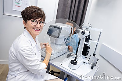 Optometrist in white scubs near refractometer Stock Photo