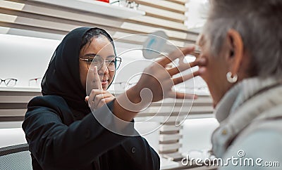 Optometry, vision and eye test with an islamic woman optician working to diagnose a customer. Doctor, optometrist and Stock Photo