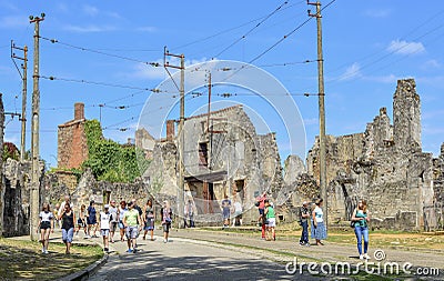 ORADOUR SUR GLANE, FRANCE - AUGUST 16, 2017: The tourists looks at the ruined building during World War 2 Editorial Stock Photo