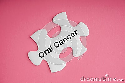 ORAL CANCER text with white jigsaw puzzle on pink background Stock Photo