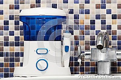 Oral hygiene, bathroom objects concept. Mouth teeth cleaning irrigator modern tool on sink. Stock Photo