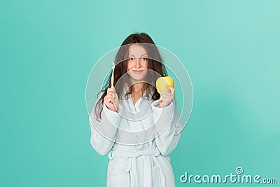 Oral hygiene. Woman bathrobe hold toothbrush and apple. Personal hygiene. Girl cleaning teeth. Freshness and cleanliness Stock Photo