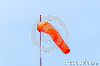 An orange airfield wind sock on a white and red pole with a red Stock Photo