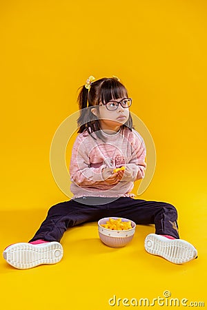 Curious serious little lady sitting on bare floor against bowl Stock Photo