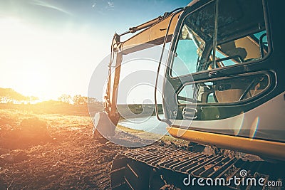 Orange backhoe is on the ground with sunset Stock Photo