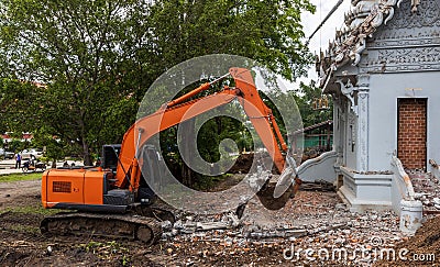 Orange backhoe to dismantle the cement crematorium Editorial Stock Photo