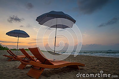 Orange beach chairs and parasols on sandy beach with morning sky Stock Photo