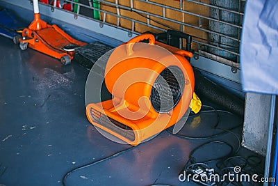 Orange blower fan machine on wet floor. Heavy Duty Industrial Portable Blower Fan on floor Used to reduce heat to racing cars. Stock Photo