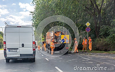 Orange car and brigade road repair workers in orange suits on the highway. Asphalt road workers repairs road Editorial Stock Photo