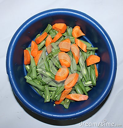 The orange carrot and green bean in the bowl. Top view with white background Stock Photo