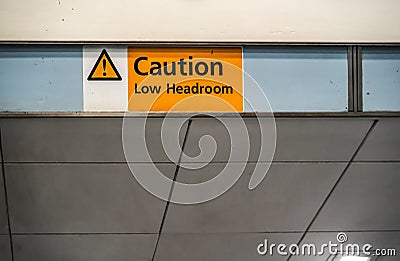 Orange ` Caution low headroom ` sign on roof above elevators Stock Photo