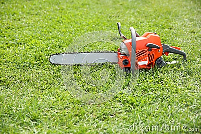 orange chainsaw on grass Stock Photo