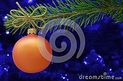Christmas card concept. Orange Christmas bauble and spruce branch with copy space. Stock Photo