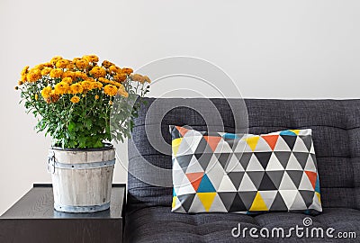 Orange chrysanthemums and bright cushion on a sofa Stock Photo