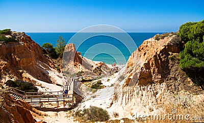 Orange cliffs, blue sea, footbridge, beach in `Falesia` in Algarve, Portugal Stock Photo