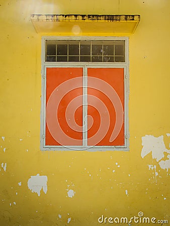 Orange closed window in old wall Stock Photo