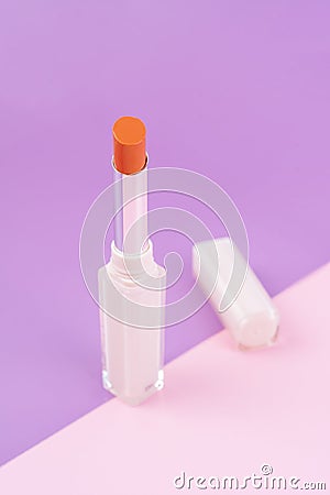 A orange color beautiful lipsticks on pink and purple background Stock Photo