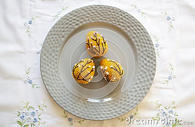 Orange crocheted Easter eggs on a plate on a white tablecloth. Easter handmade Stock Photo