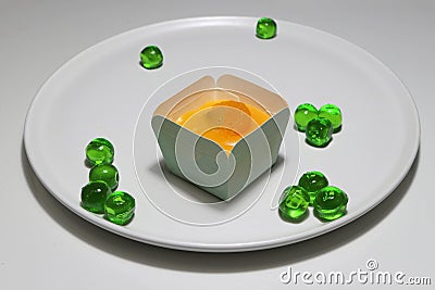 Orange cupcake and topping with orange sacs and jelly green round in the white dish. Stock Photo