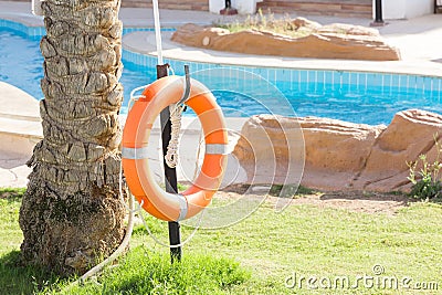 Orange emergency lifebuoy hanging on fence near pool on vacation at the hotel with copy space Stock Photo
