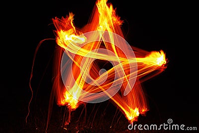 Orange fire star. Drawing of a star with fire on a black background. Stock Photo