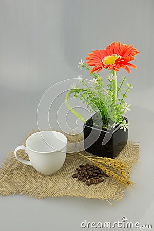 Orange flower in a vase with coffee cup on gunny textile isolate Stock Photo