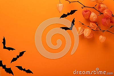 Orange Halloween background. Flock of black bats and branch of dry orange flowersfor Halloween. Black paper bat silhouettes on Stock Photo