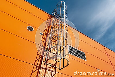Orange industrial building wall with metal ladder Stock Photo