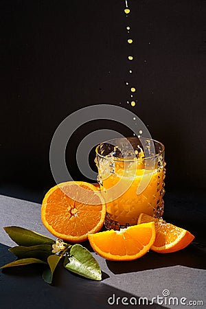 Orange juice drops into glass with orange juice, sliced oranges with blossom Stock Photo