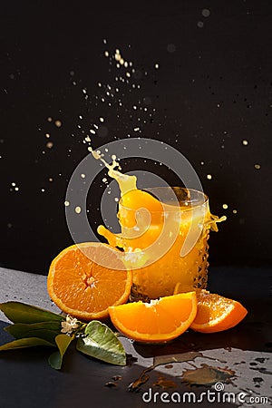 Orange juice splash in the bright sun with black background Stock Photo