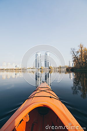 Red kayak sailing towards modern buildings on the waters of Dnipro river in Kyiv, Ukraine Stock Photo