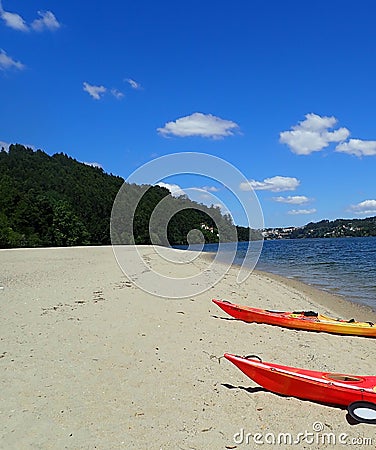 Orange kayaks on the sand on shore of river Stock Photo