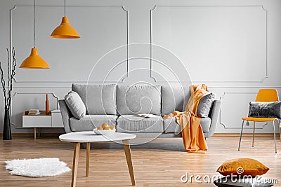 Orange lamp above grey scandinavian sofa Stock Photo