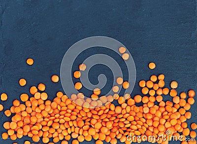 Orange lentil lies on a black stone background. Toning Stock Photo