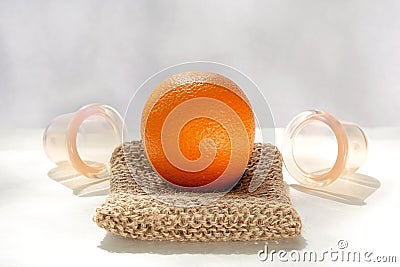 The orange lies on a mesh washcloth made from natural fibers, and next to it are vacuum banks. Stock Photo