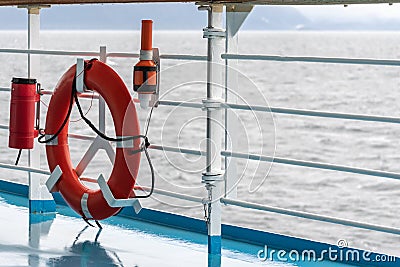 Orange lifebuoy emergency gear/ device/ equipment with reflective silver strips on cruise ship deck. Stock Photo