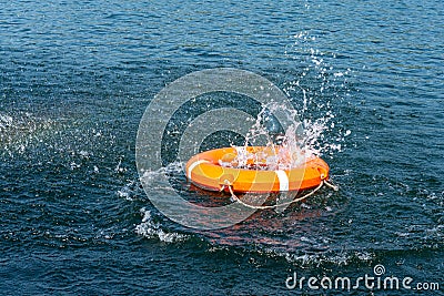 Orange lifebuoy in the sea. The rescue ring fell with a splash on the surface of the water, motion blur . Stock Photo