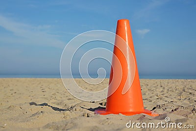 Orange marking cone in middle of sand beach with blue sky Stock Photo