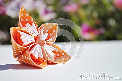 Orange origami flower on floral background. Copy space. Stock Photo