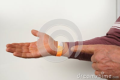 orange paper wristband mockup on persons arm. Clear adhesive bangle wristlet sticker with entry number on male hand of middle-aged Stock Photo