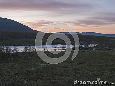 Orange pink sunset at wild water of Vuojatadno river rapids, mountain and birch tree forest. Beatiful northern artic Stock Photo