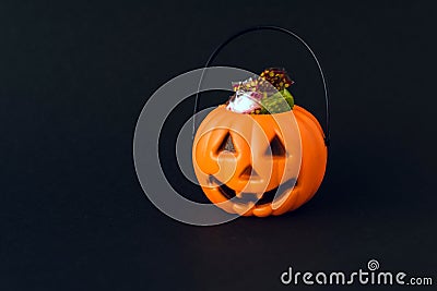 Orange plastic candy basket in the shape of a pumpkin jackolantern on a black background Stock Photo