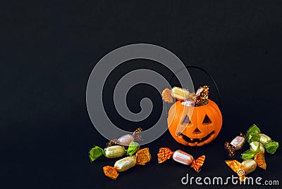 Orange plastic candy basket in the shape of a pumpkin jackolantern on a black background Stock Photo