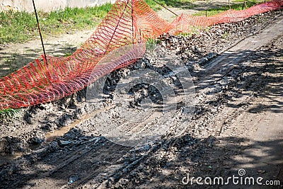 Orange plastic safety net or barrier on the street to protect excavating construction site close up Stock Photo