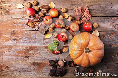 Orange pumpkin with cardoncelli mashrooms, apples, walnuts and colorful leaves on old rustic wooden boards. Autumn Thanksgiving Stock Photo